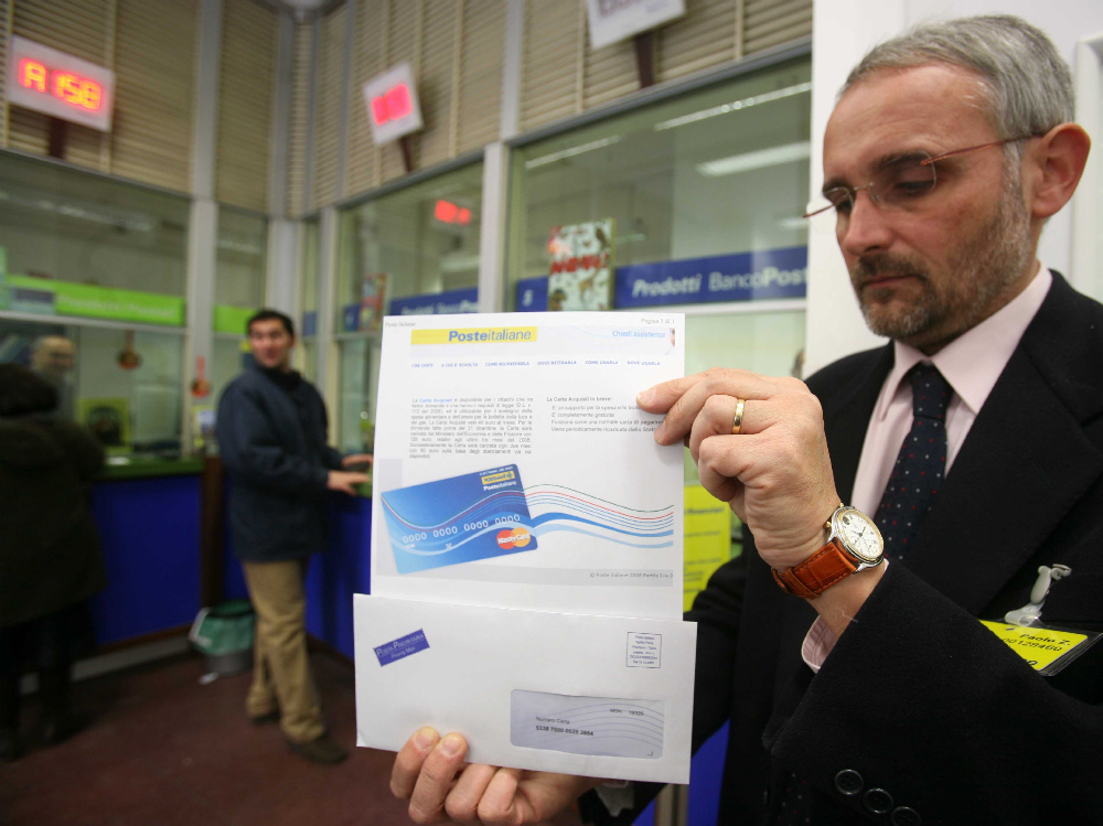 Il direttore delle Poste di Piazza Isolo mostra la social card in  distribuzione agli sportelli