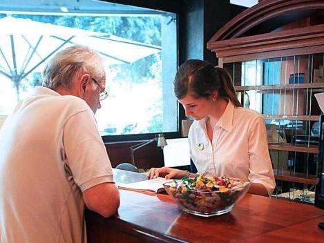 Un turista viene accolto alla reception di un albergo, sono in corso controlli